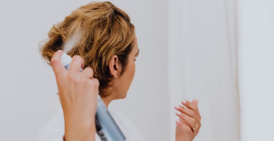 woman applying hair spray