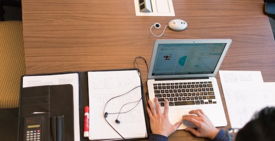 person on laptop with notebook open and earbuds