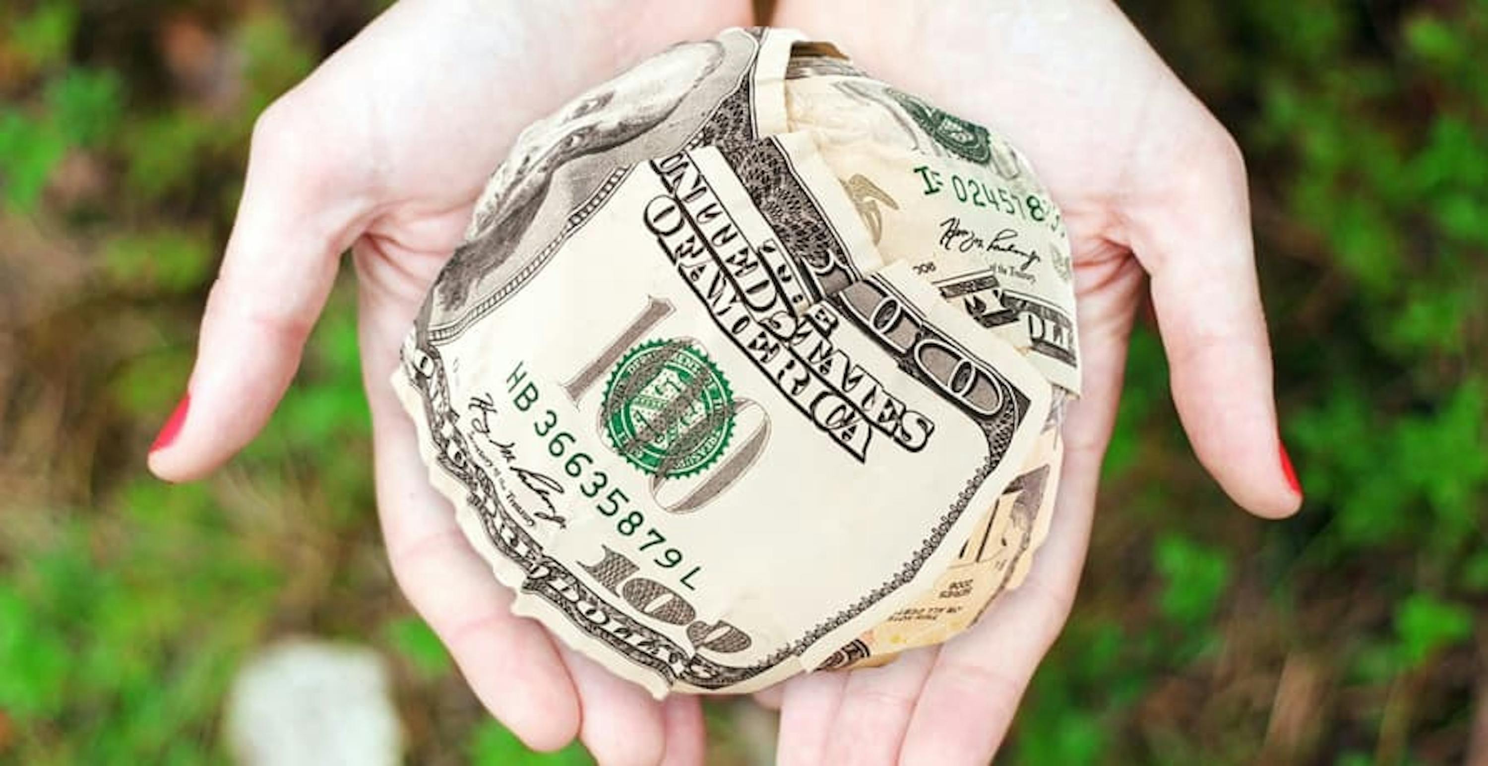 woman holding dollar bills with plants in the backgroun