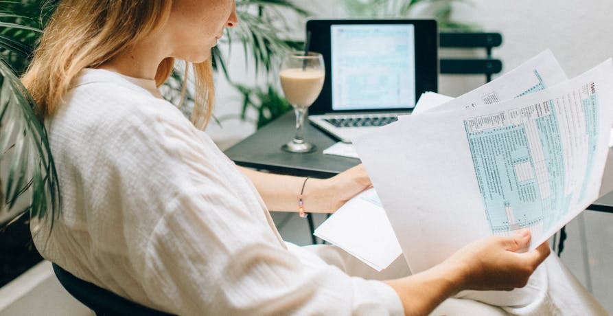 femme lisant plusieurs documents assise à son bureau