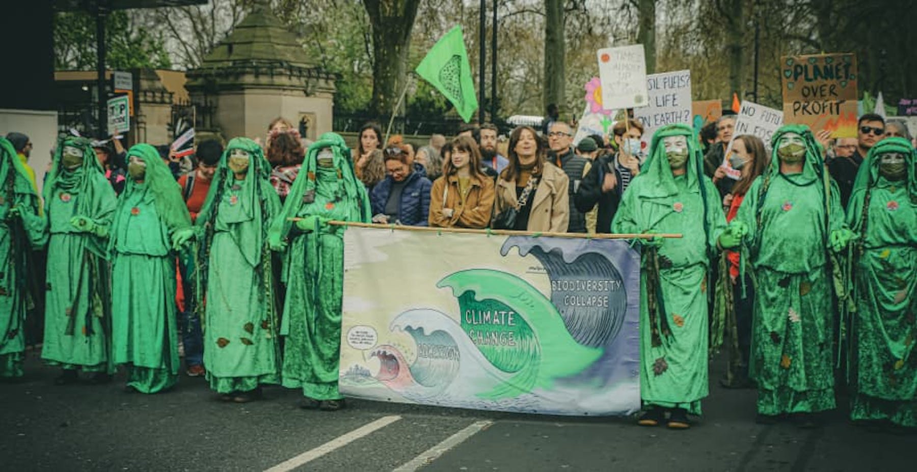 Climate change protesters holding a banner and painted green 