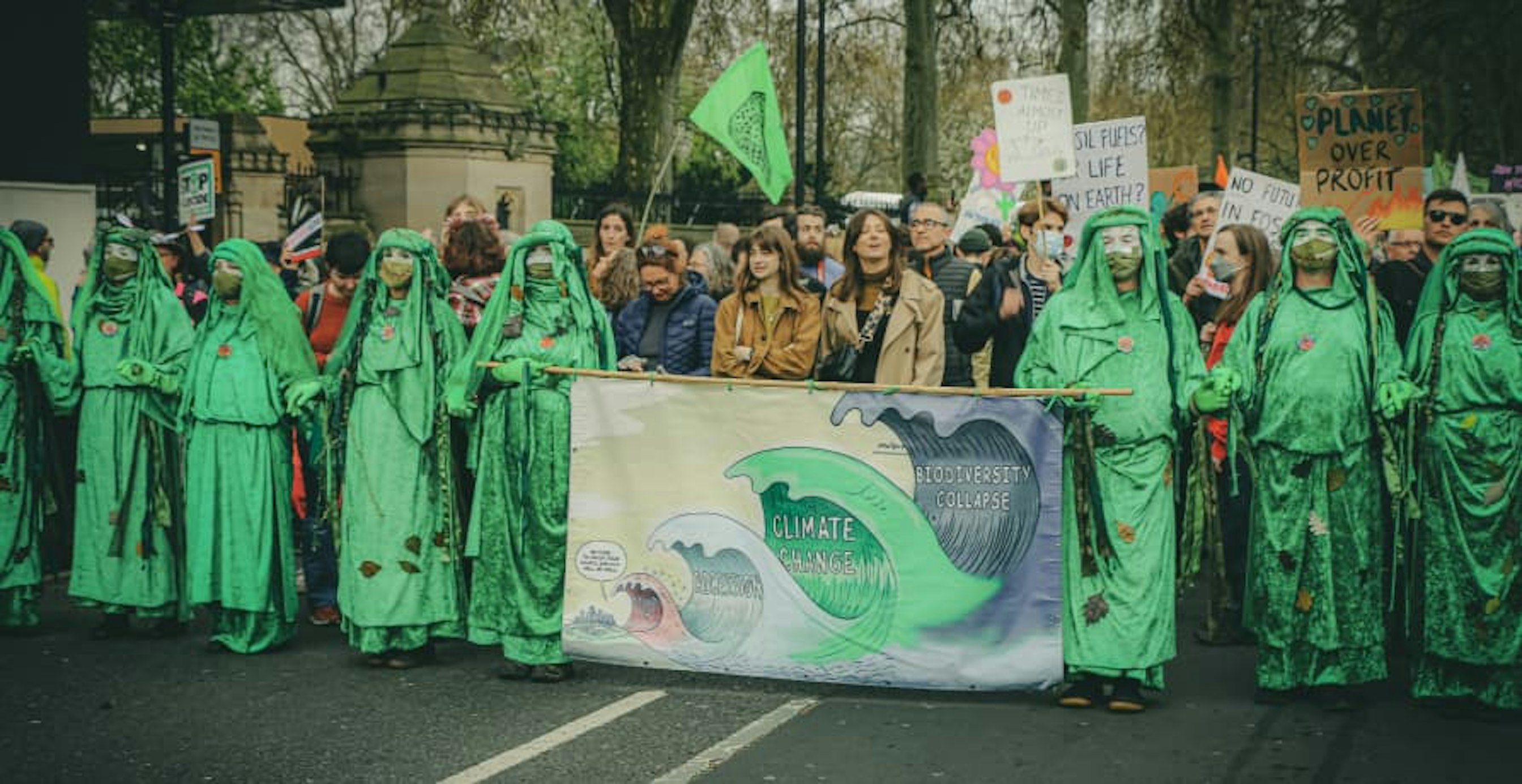 Climate change protesters holding a banner and painted green