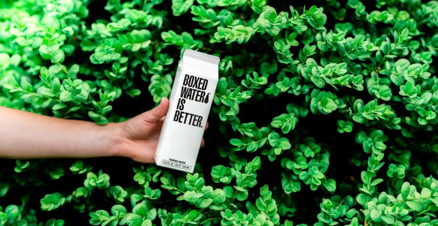 boxed water behind green bush