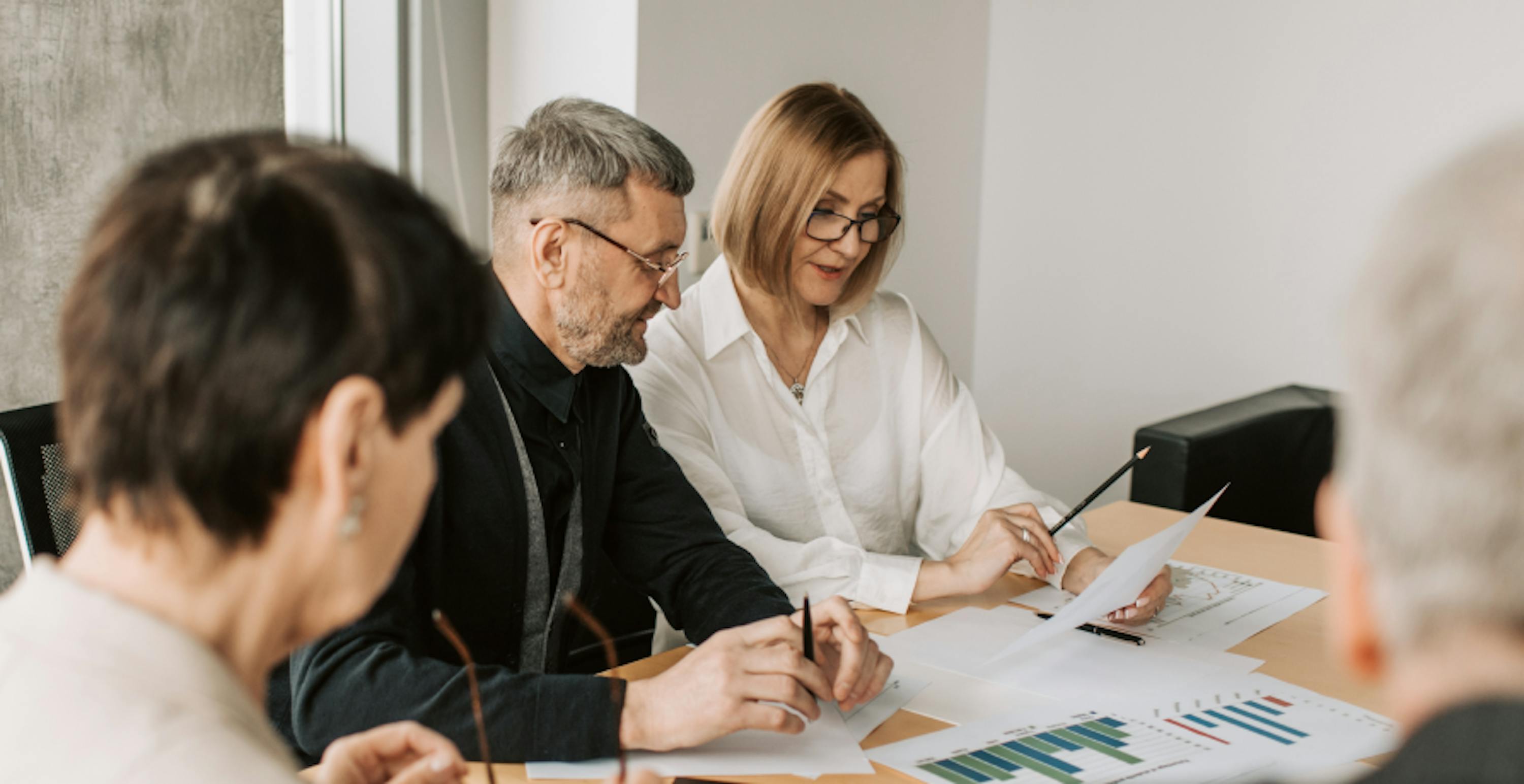 trois personnes analysant des graphiques sur un bureau