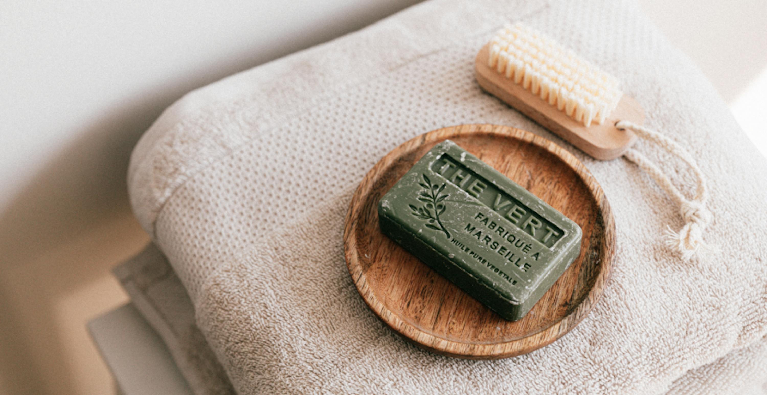 un savon portant la mention "thé vert fabriqué à Marseille" posé sur une serviette de douche