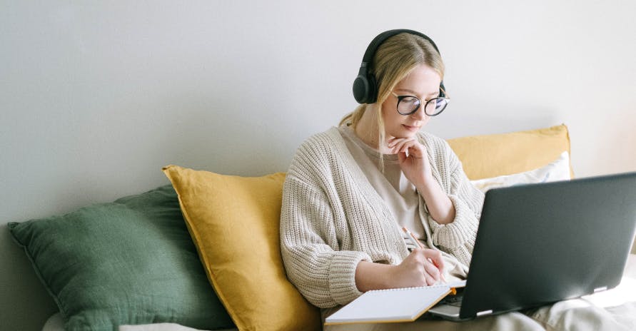 Femme écoutant de la musique et en écrivant devant son ordinateur