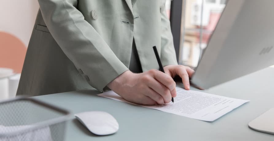 woman in a suit working on a report in front of office computer