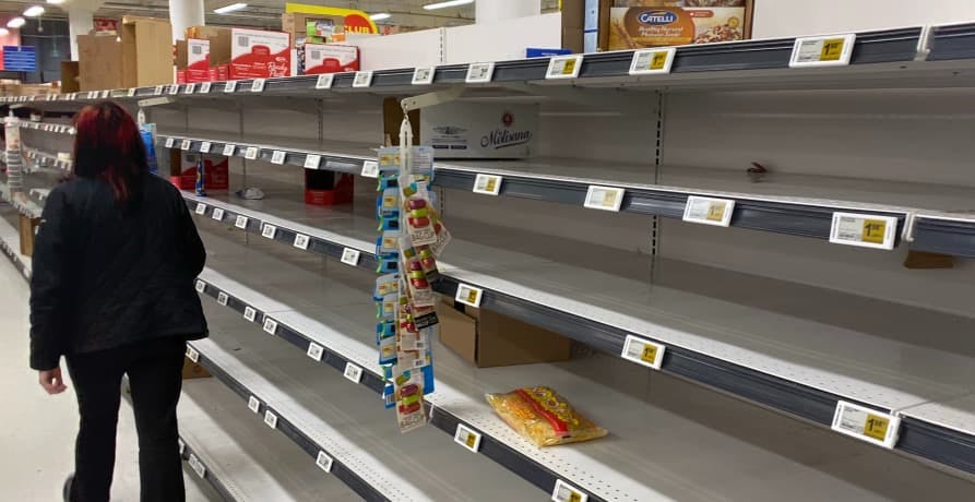 person walking by empty supermarket shelves