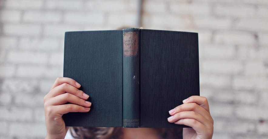 person reading a book covering their face