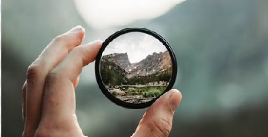 person looking at scenic view through a magnifying glass