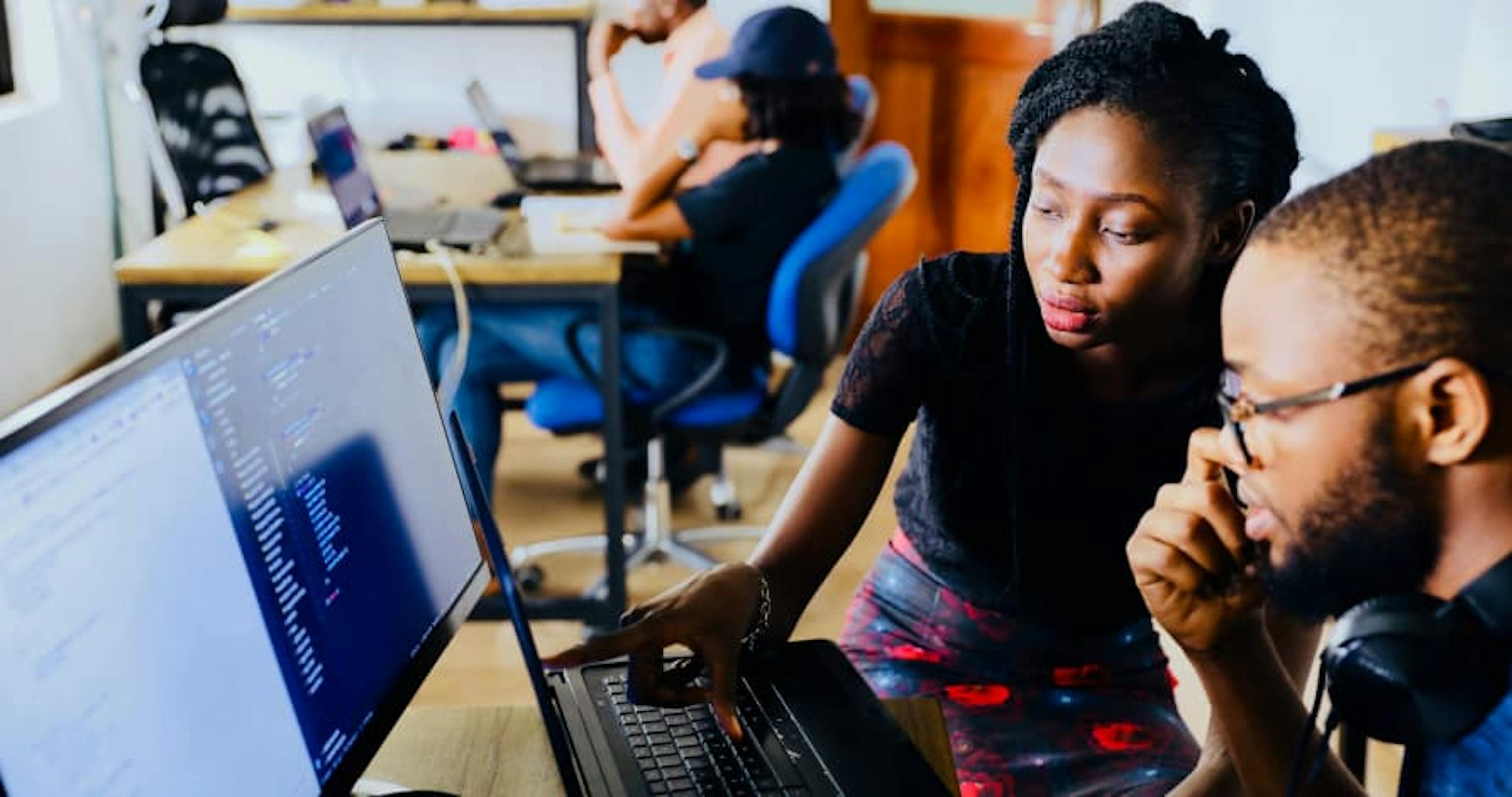 people on laptops in small workspace