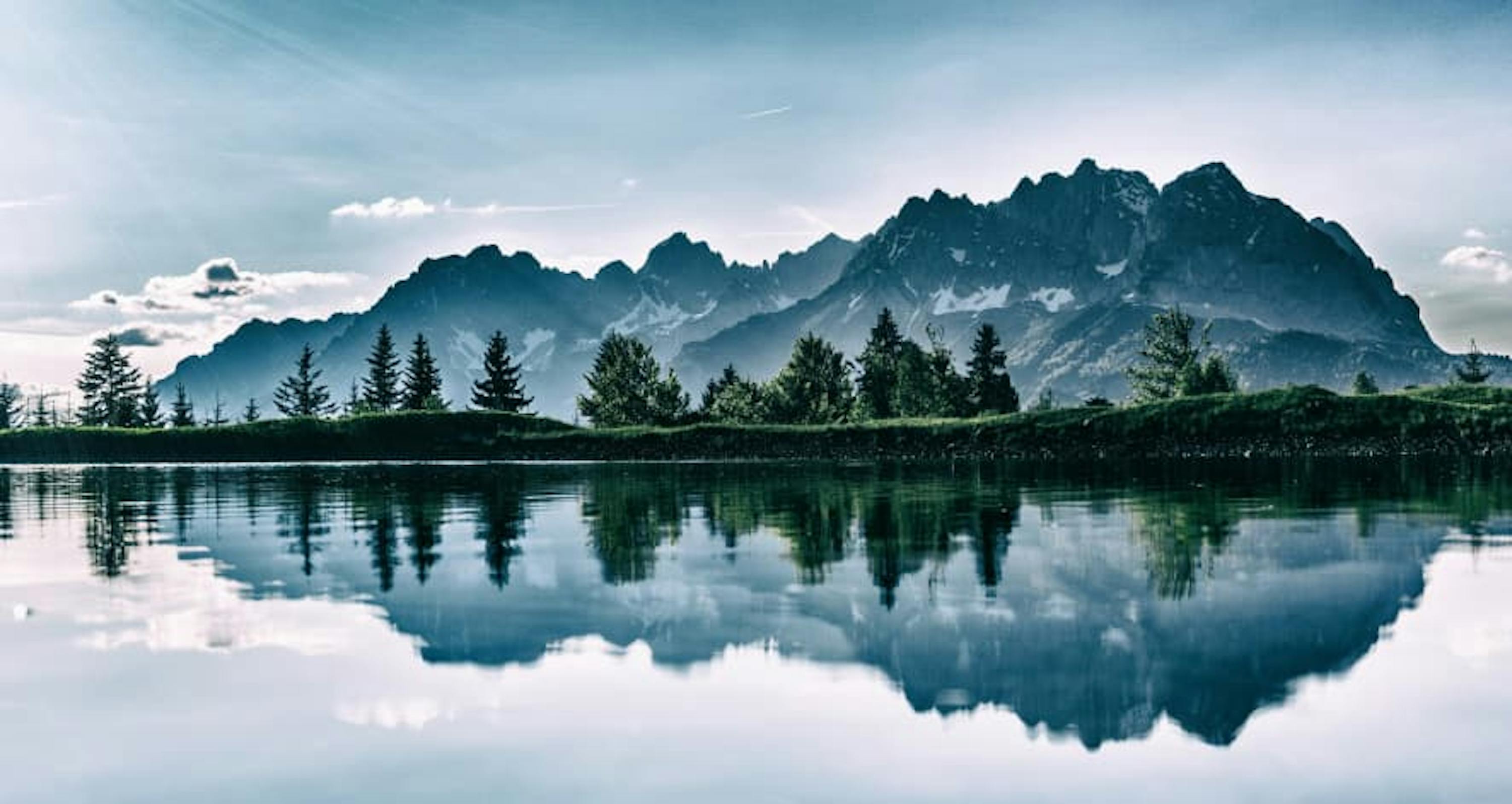 view of mountain scape and trees on water