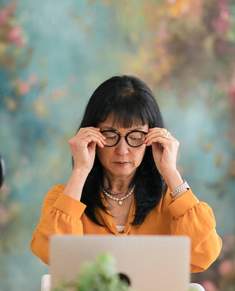A woman wearing glasses in front of a laptop