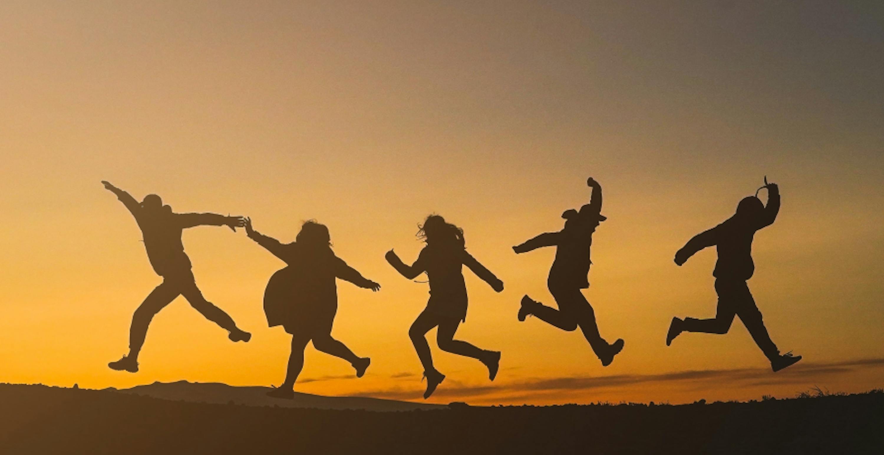 des personnes sautant en l'air devant le coucher de soleil