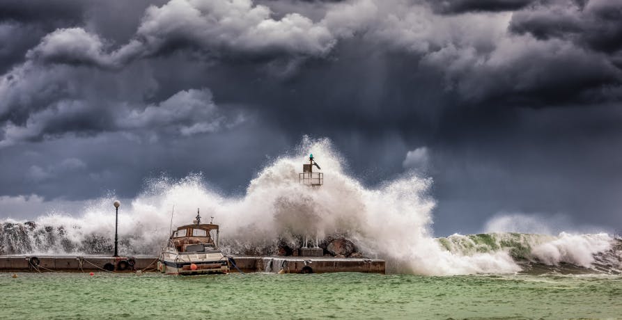 une immense vague qui tombe sur un phare sous un ciel noir