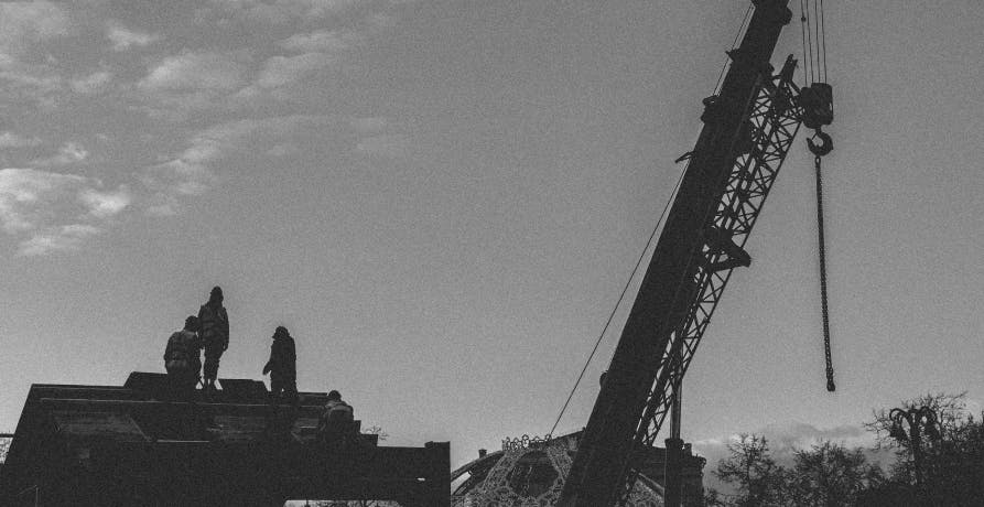 une image en noir et blanc montrant une grue de chantier devant une maison
