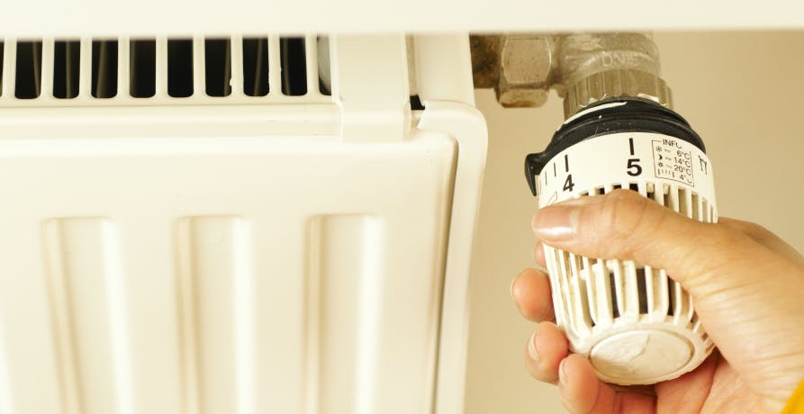main sur le thermostat d'un radiateur