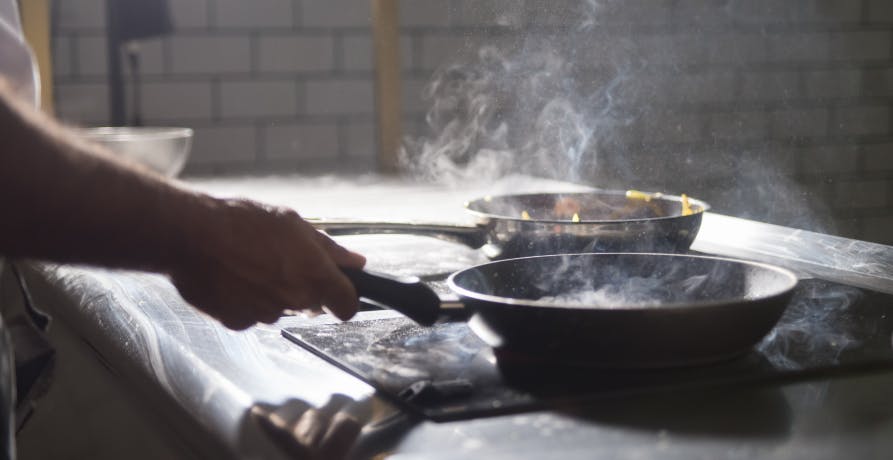 woman cooking with teflon pan on induction stove