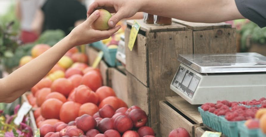 vendor and customer holding an apple in a market