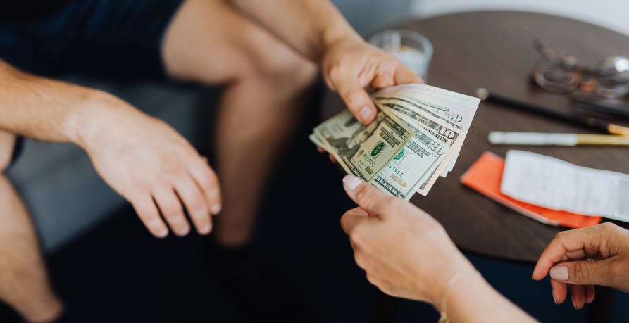 someone handing someone else cash USD