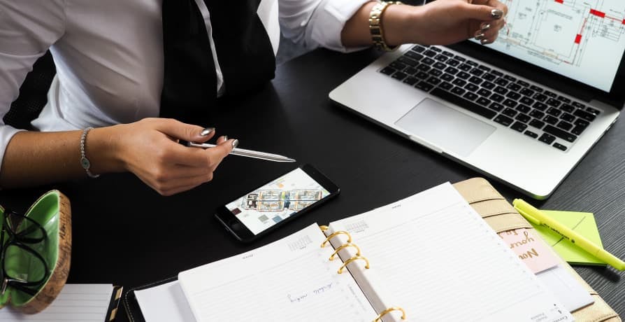 person with graph on laptop, phone, notebook, pen