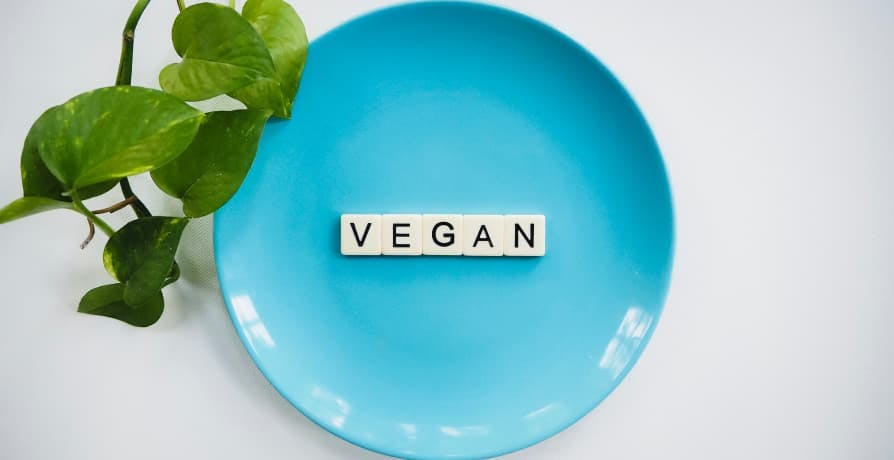 blue plate with green plant next to it spelling out vegan with scrabble letters