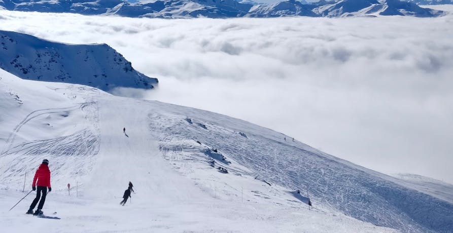 plusieurs skieurs dévalent une montagne enneigée