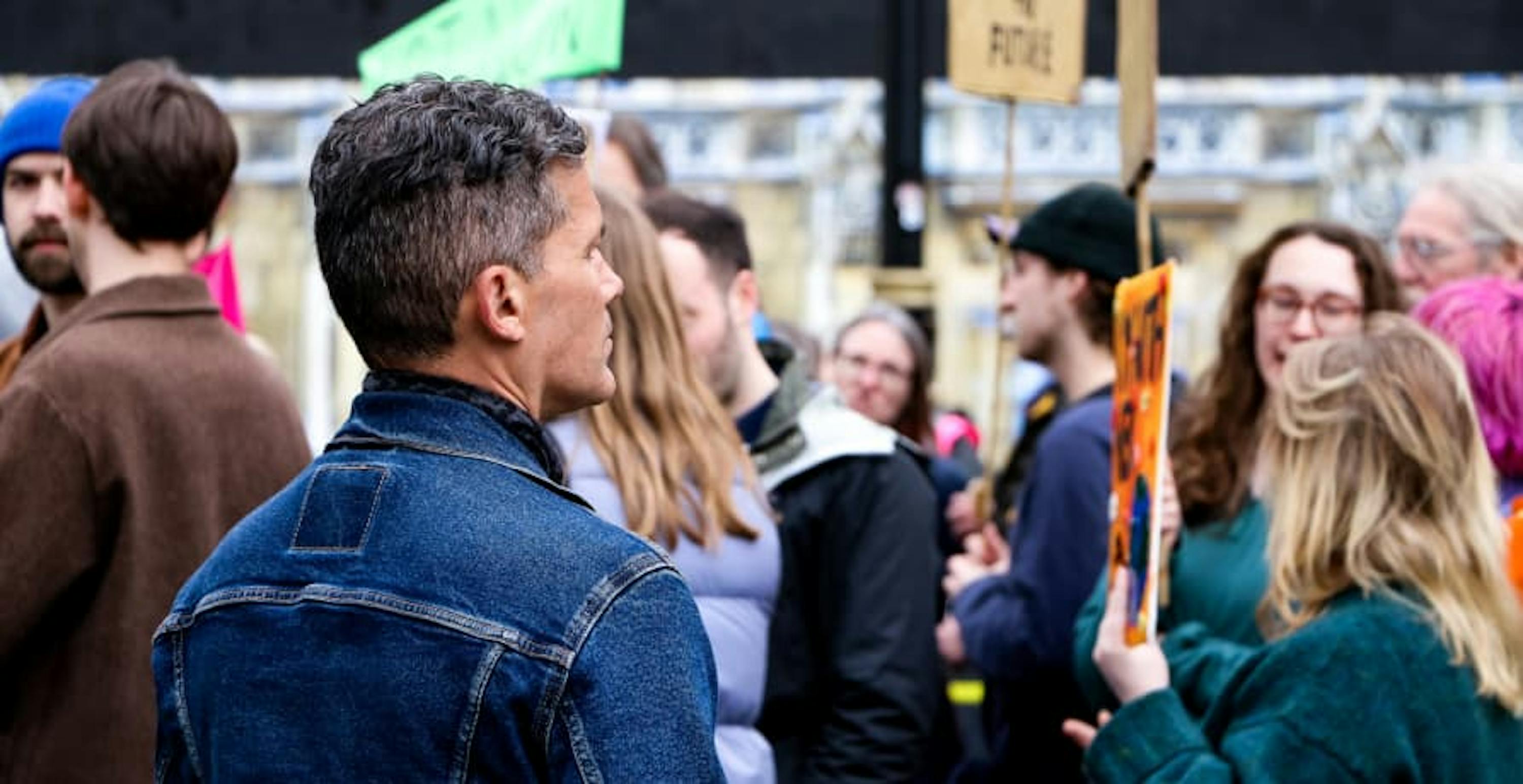 Climate change protestors standing talking, holding signs