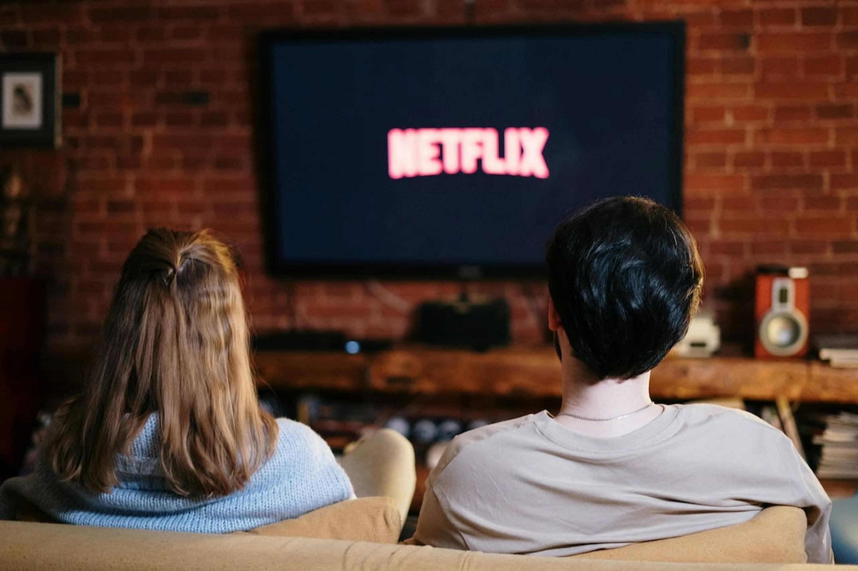 Personnes assises sur un canapé en train de regarder netflix