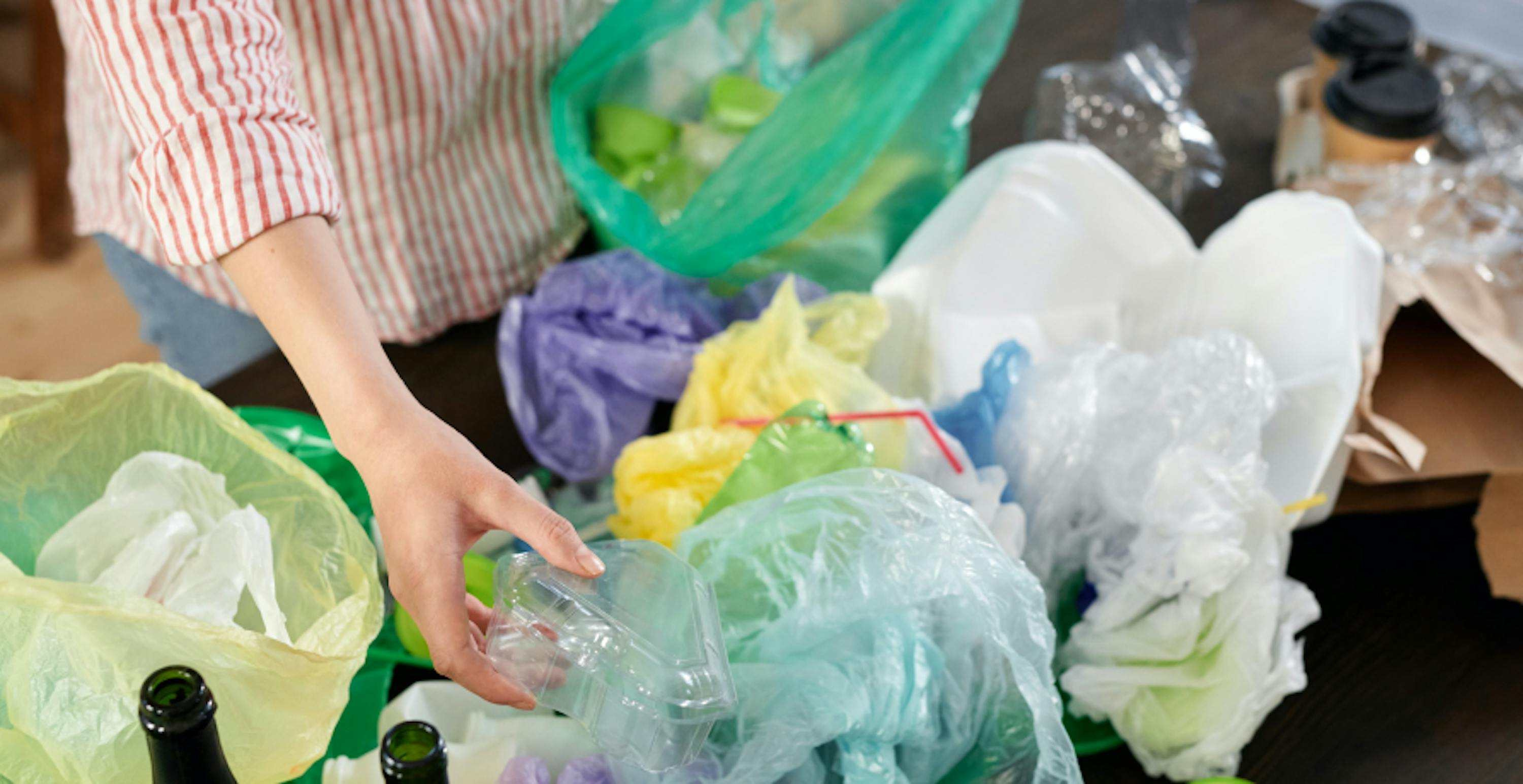 plusieurs sachets plastiques éparpillés sur une table avec une femme qui les trie