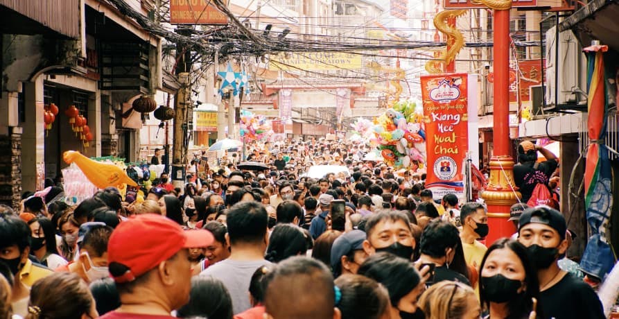 large crowds of people walking down narrow city street