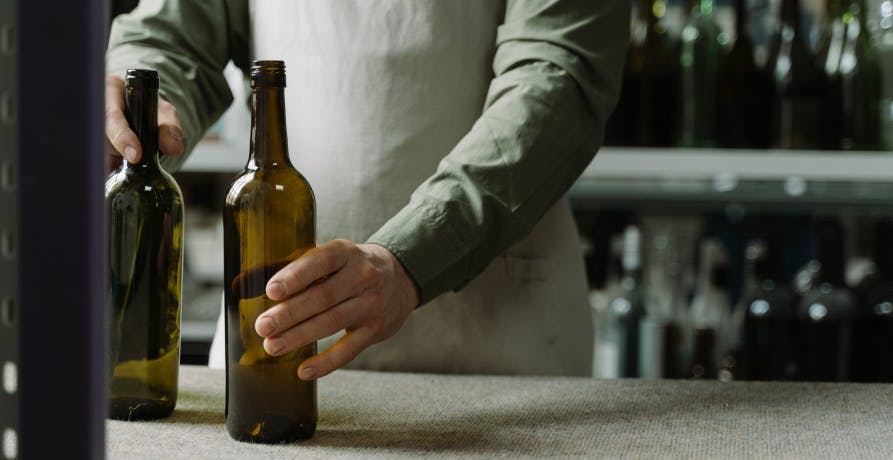 un homme posant deux bouteille en verre sur une table