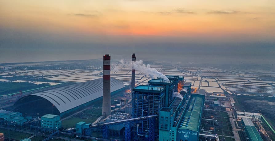 factories producing emissions in sunset