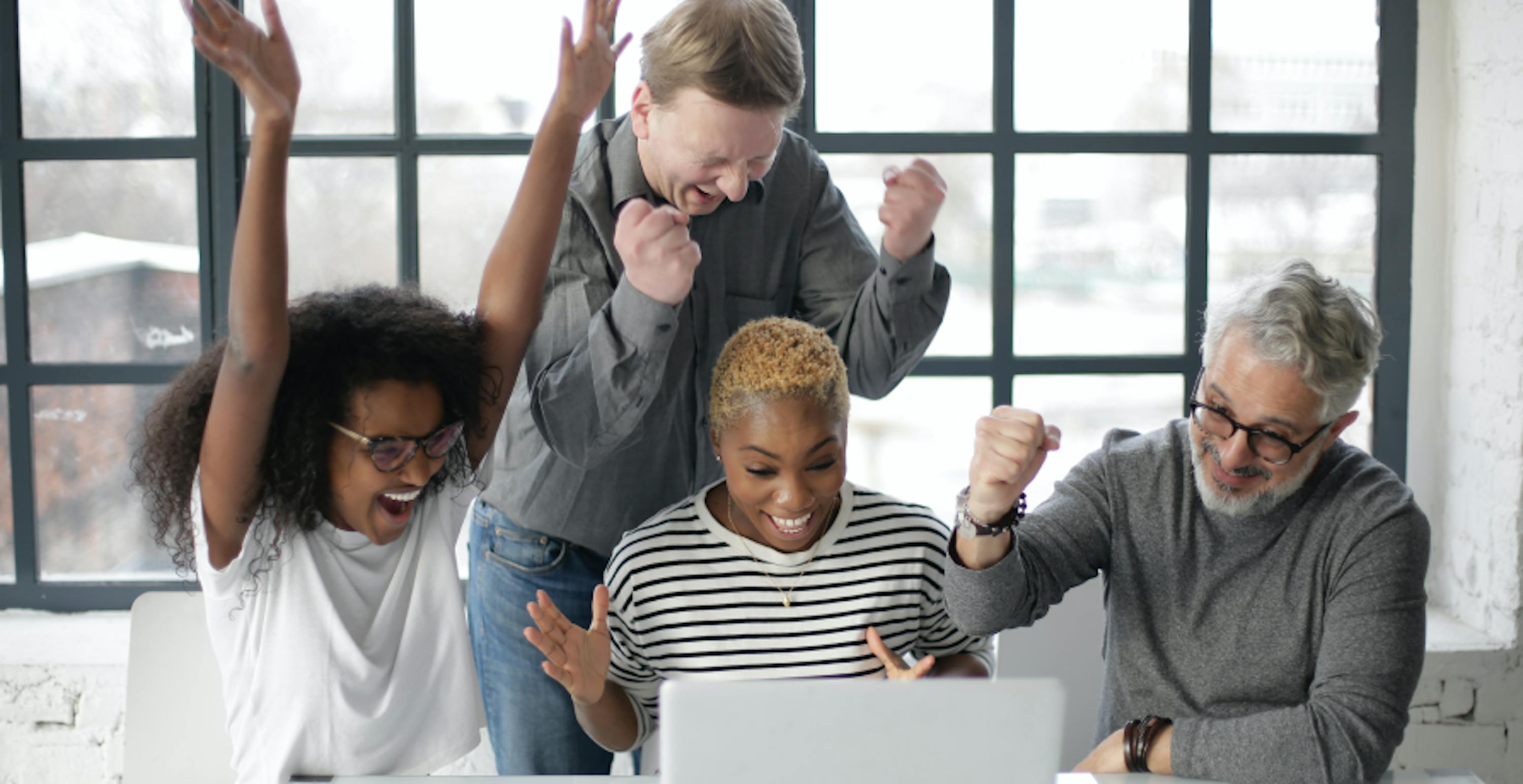 quatre personnes montrant leur joie devant un ordinateur