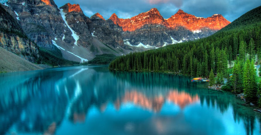 teal blue lake with reflection of mountains