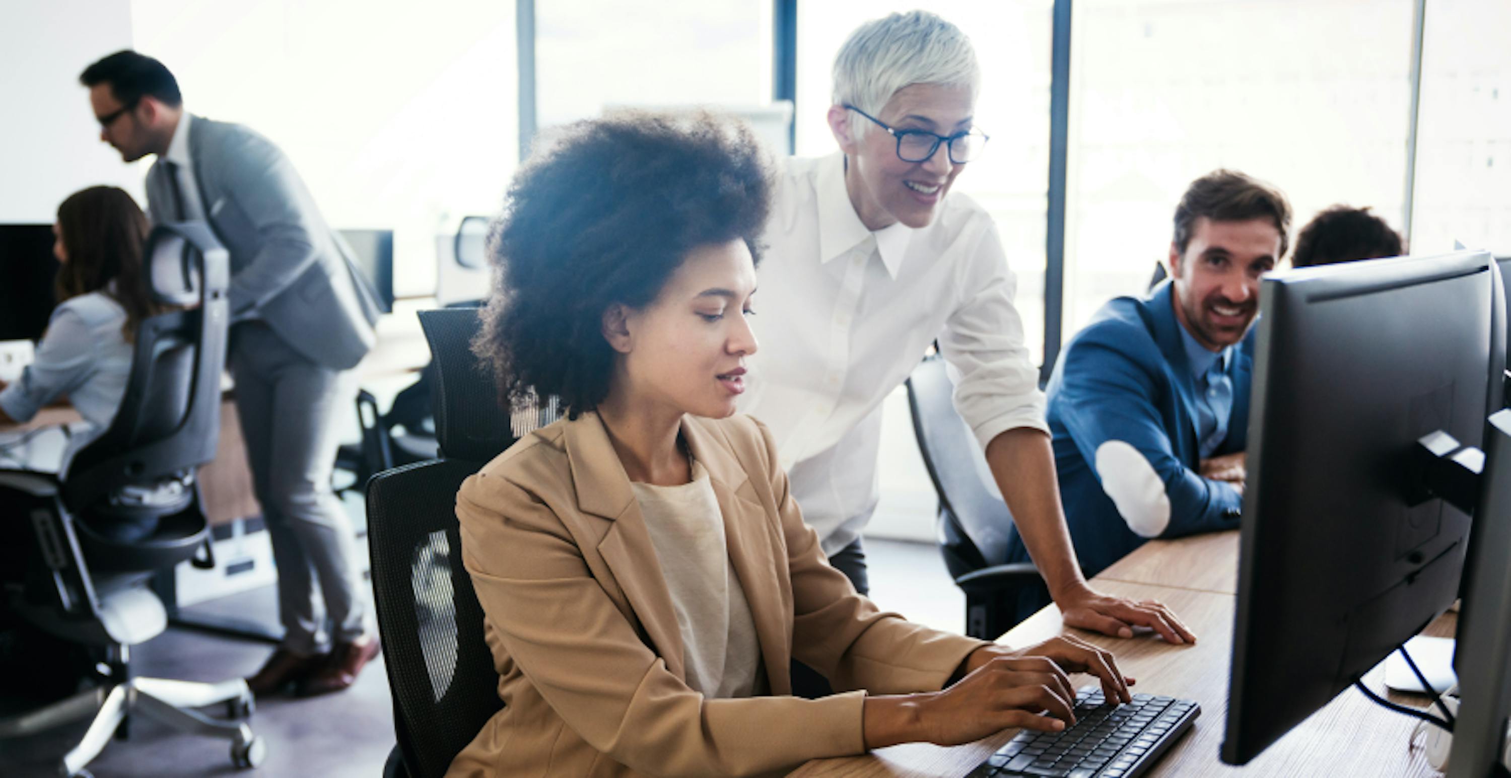 des personnes dans un open space devant des ordinateurs