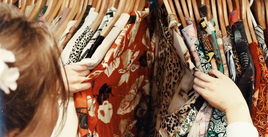 girl searching for clothes on rack in store