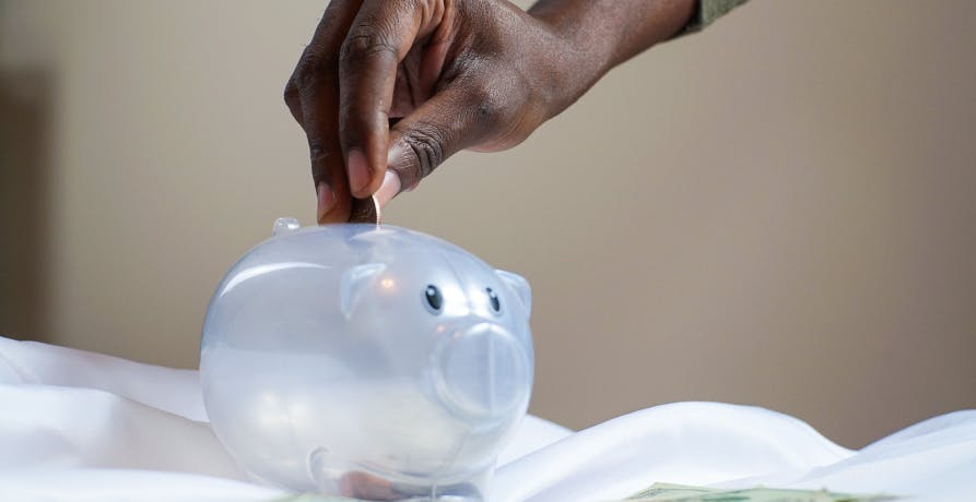 man placing coin in piggy bank