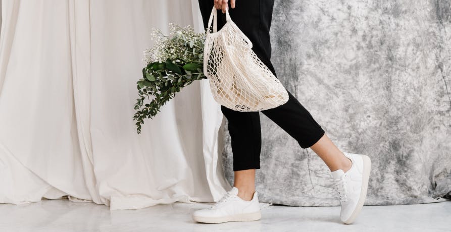 une personne tenant un sac de courses contenant un bouquet de fleurs