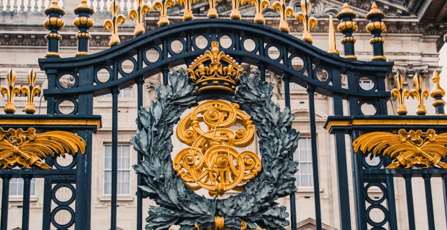Close up of Buckingham Palace gate with gold decoration and the royal coat of arms and grown