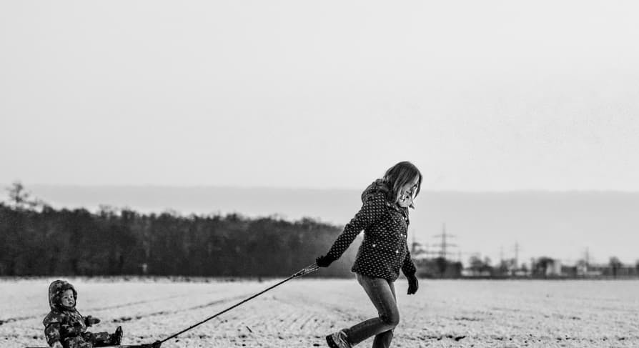 woman dragging son in snowsled