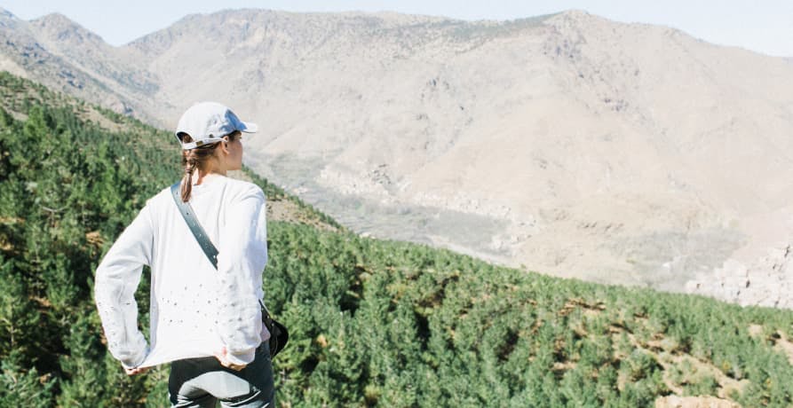 woman standing on top of a hill overlooking mountains and countryside