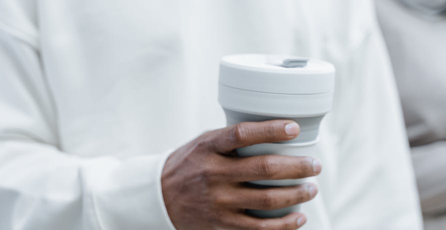 person holding reusable coffee cup