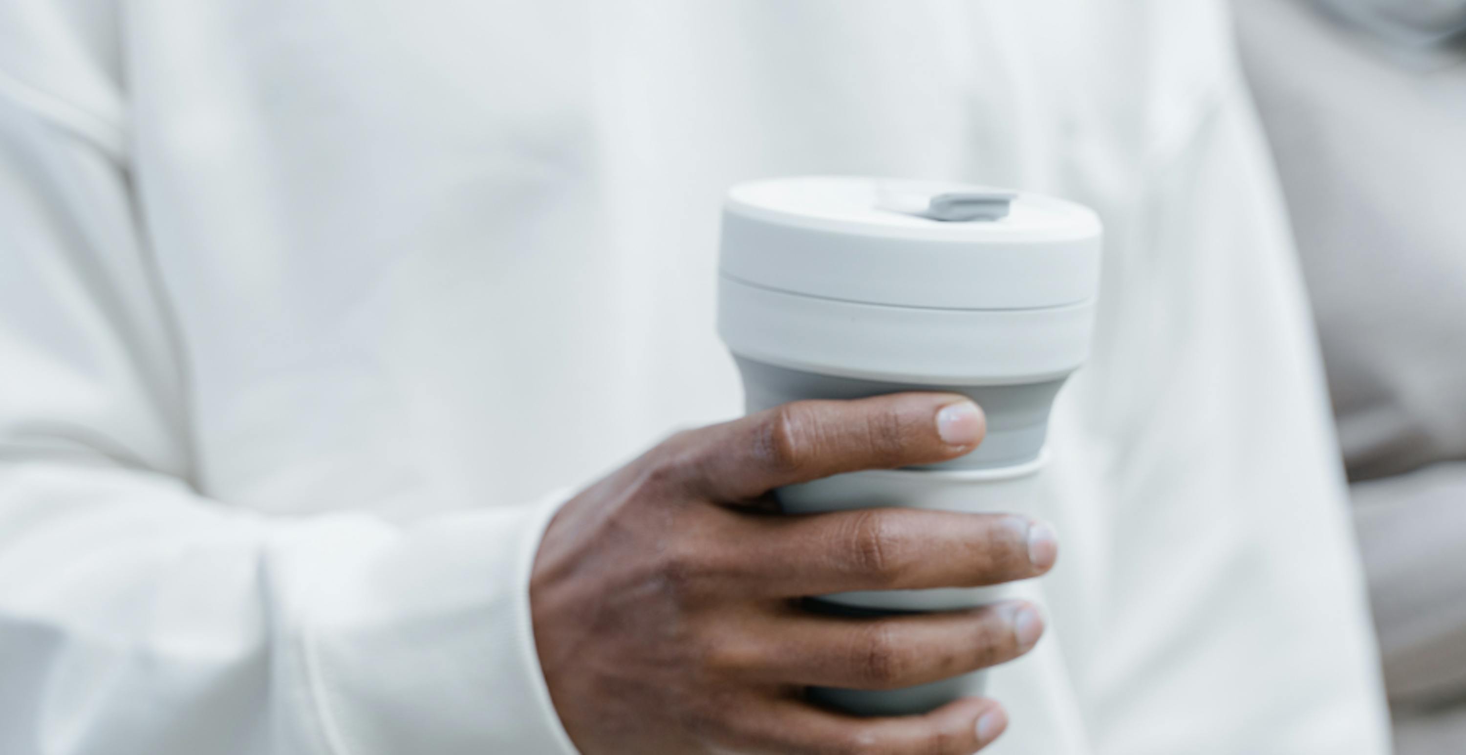 person holding reusable coffee cup