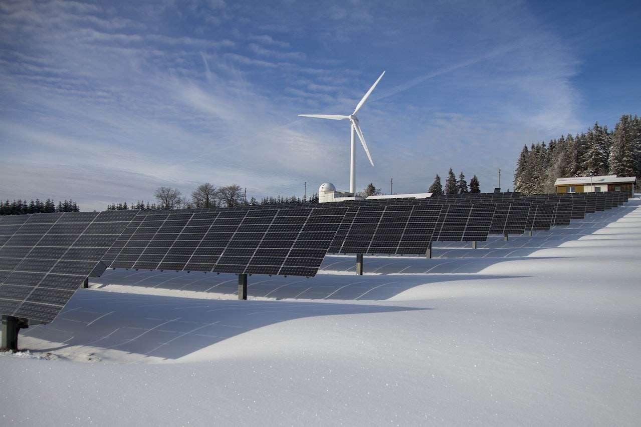 Panneaux solaires sur la neige avec éolienne sous un ciel dégagé