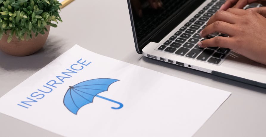 person on laptop with insurance policy next to it