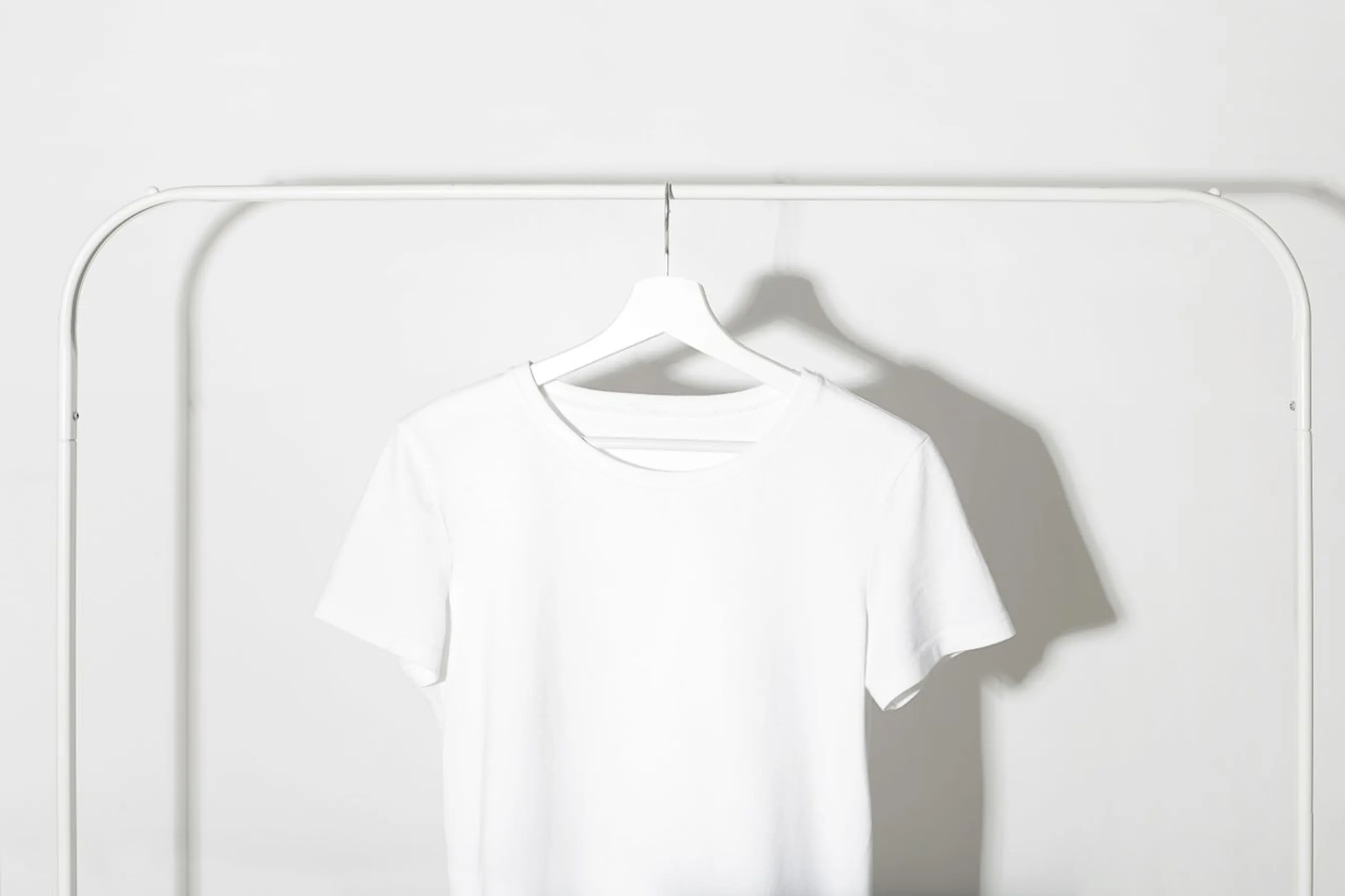 T-shirt blanc uni suspendu sur un cintre, sans motif ni logo.