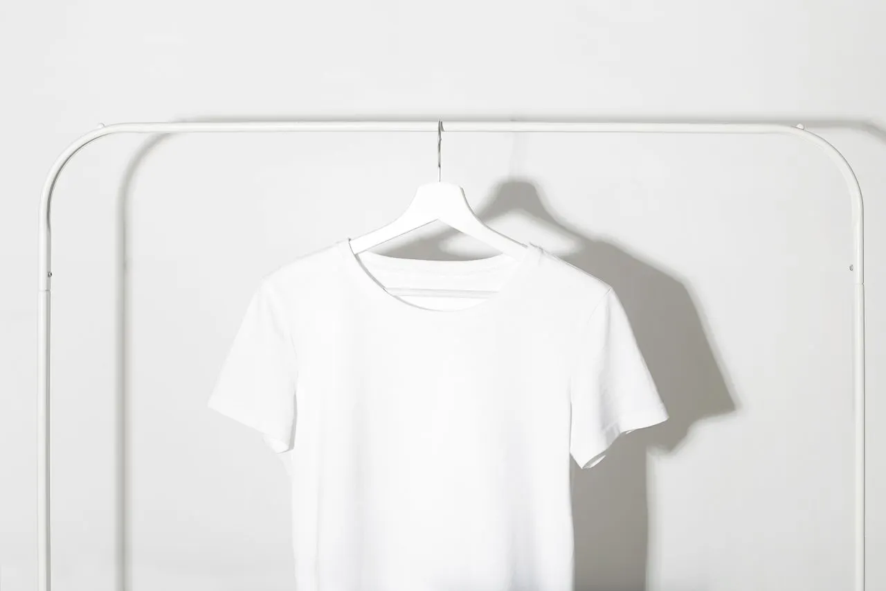 T-shirt blanc uni suspendu sur un cintre, sans motif ni logo.