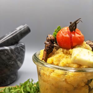 Grasshopper polenta in a jar topped with a grilled cherry tomato