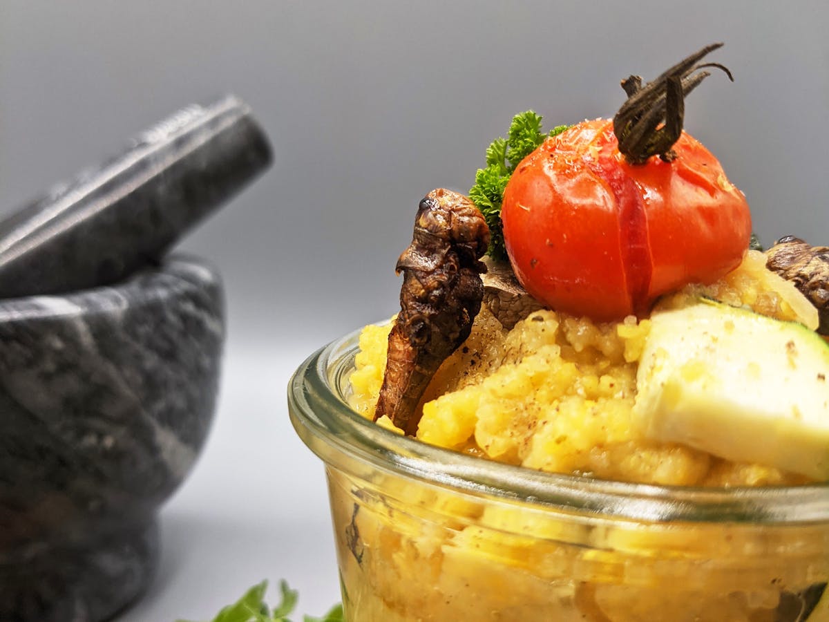 Grasshopper polenta in a jar topped with a grilled cherry tomato